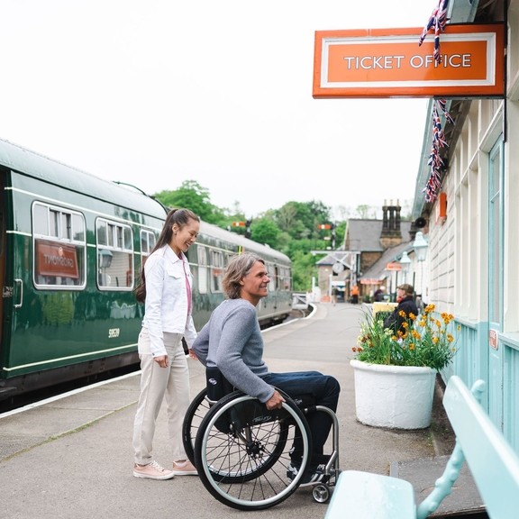 Ein Mann im Rollstuhl und eine Frau, die den Fahrkartenschalter des Bahnhofs Grosmont betreten wollen
